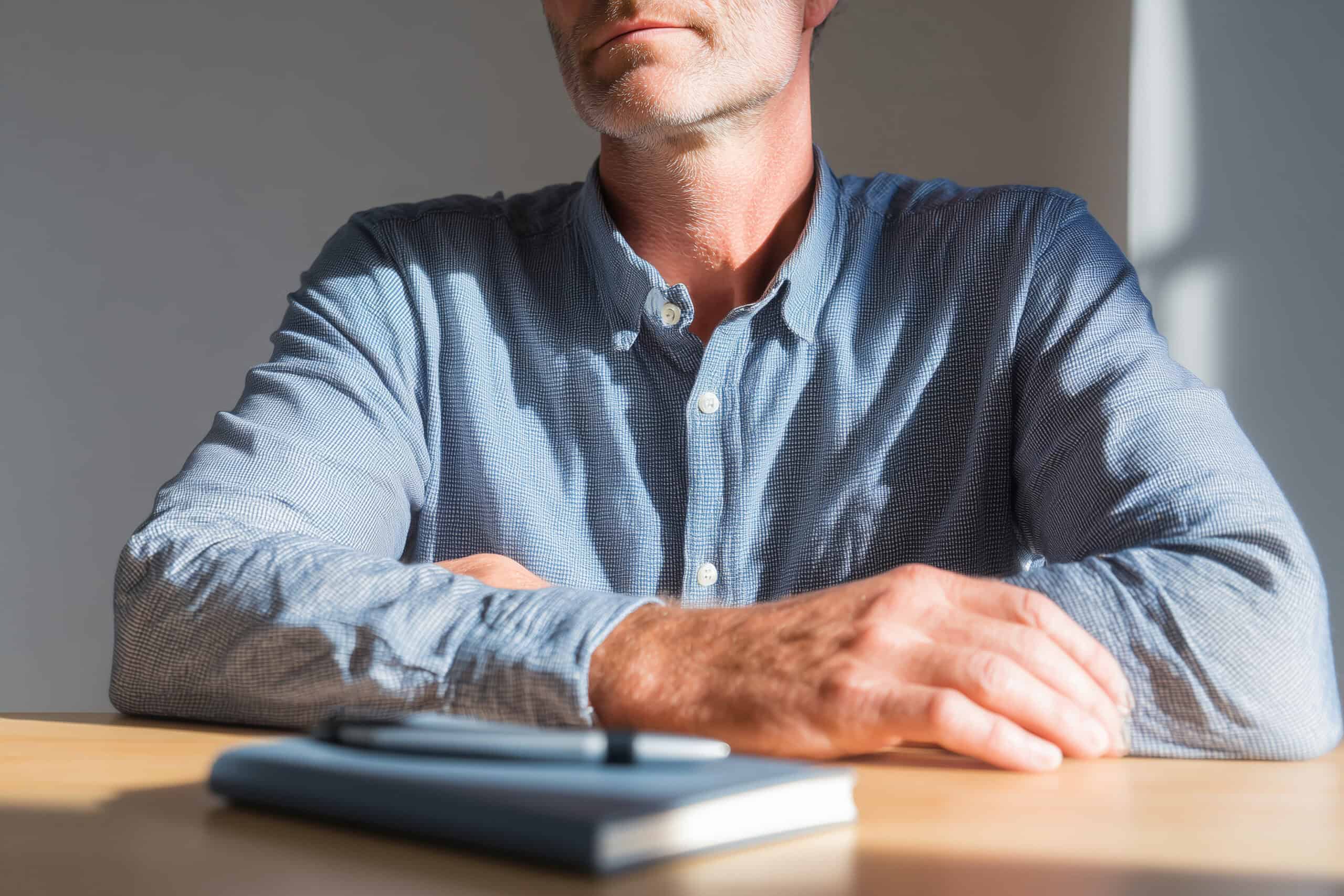 Mid 40s man sitting at a table with only a notebook and pen s 4aca2599 59a6 44e4 a45a 7c3edf1895a0 0 scaled